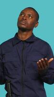 Vertical Security guard tasked with restricting unwanted access looking to sky, praying. Portrait of bodyguard waiting for miracle, doing spreading arms gesture, studio background, camera A video