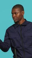 Vertical Portrait of security guard pointing finger at intruders while overseeing premises. Private law enforcement worker scolding unwanted trespassers, studio backdrop, camera A video