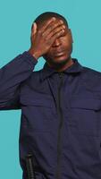 Vertical Portrait of tired security guard suffering from painful headache while overseeing premises. Private law enforcement worker feeling ache from fatigue, studio backdrop, camera A video