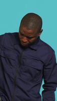Vertical Portrait of security guard removing cane from belt while overseeing premises. Private law enforcement worker pointing to truncheon, threatening to subdue criminals, studio backdrop, camera A video