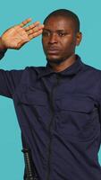 Vertical Security guard doing salute hand gesture, preparing to start job of deterring criminals. Portrait of bodyguard doing greeting gesturing and military pose, studio background, camera A video