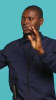 Vertical Portrait of security agent doing crowd control, securing assigned post, studio background. African american guardian pushing back unwanted trespassers, handling security breaches, camera A video
