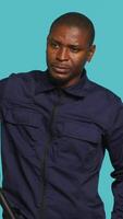 Vertical Portrait of security guard menacingly smacking hand with baton while overseeing premises. Private law enforcement worker cautioning trespassers with truncheon, studio backdrop, camera A video