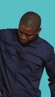 Vertical Security guard removing baton from belt, preparing to attack suspects. Portrait of bodyguard pointing finger towards truncheon, threatening to subdue criminals, studio background, camera A video