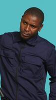 Vertical Security guard smacking hand with baton, intimidating suspects. Portrait of bodyguard showing truncheon, threatening to subdue criminals, shaking head, studio background, camera A video