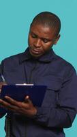 Vertical Portrait of security agent holding clipboard, taking notes, receiving orders to secure assigned post, studio background. Guardian maintains logs of observations, handling security breaches, camera A video