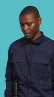 Vertical Bored security guard preventing criminal activity, patrolling around premises to deter criminals. Portrait of weary bodyguard walking around, lacking activity, studio background, camera A video