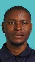 Vertical Headshot portrait of african american security agent isolated against colored studio background. Close up shot of guardian securing assigned post standing over studio backdrop, camera A video