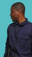 Vertical Portrait of security guard looking around while overseeing premises. Private law enforcement worker doing surveillance job, inspecting location, studio backdrop, camera A video