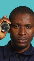 Vertical Headshot portrait of security employee tasked with evicting trespassers, turning on flashlight. Close up shot of patrolling agent using lantern, spotting intruders, studio background, camera A video