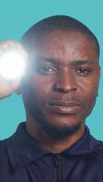 Vertical Headshot portrait of security guardian catching intruders with flashlight. Close up shot of private law enforcement employee detecting trespassers with lantern, studio backdrop, camera A video