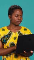Vertical Young woman freelancer navigating on online webpages in studio, browsing information on device connected to internet. Charming traditional girl carries a portable pc. Camera A. video