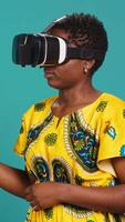 Vertical Happy confident woman uses vr headset with 3d visual simulation, wearing virtual reality smart glasses for a modern high tech experience. Person in traditional tribal clothes. Camera A. video