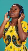 Vertical Carefree relaxed woman listening to music and dancing in the studio, having fun with a new groovy playlist. Happy optimistic person enjoys radio songs on her audio headset. Camera A. video