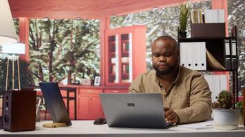 imprenditore seduta a il suo scrivania Lavorando su il computer portatile con senza fili tecnologia per a distanza lavoro efficienza. analizzando dati e sviluppando strategie, riuscito telelavoro a partire dal casa ufficio. telecamera b. video