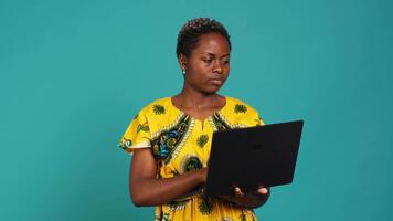Young woman freelancer navigating on online webpages in studio, browsing information on device connected to internet. Charming traditional girl carries a portable pc. Camera A. video