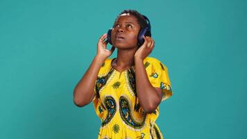 Carefree relaxed woman listening to music and dancing in the studio, having fun with a new groovy playlist. Happy optimistic person enjoys radio songs on her audio headset. Camera A. video