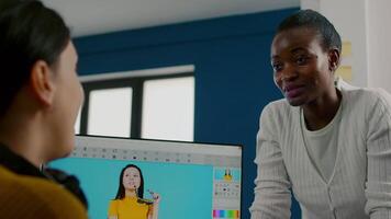 Team of multiethnic retouchers working with modern photo editing software app in digital multimedia company. Project manager consulting designer colleague discussing about retouching portrait video