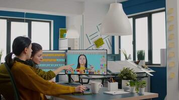 Confident women photo editors sitting in creative workplace retouching photos, art director checking color greding technic talking with worker. Retouchers editing with graphic tablet and stylus pencil video