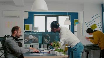 multiétnico equipe partilha Ideias sobre industrial projeto usando dois monitores com 3d engrenagens e metálico braçadeira usando cafajeste Programas. industrial engenheiro e Preto Gerente inovando protótipo do motor video
