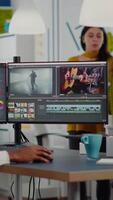 Black videographer putting on headset editing movie using post production software working in creative start up agency office. African editor processing footage on computer with dual displays video