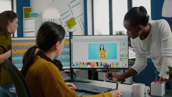 Diverse photo editors sitting in creative workplace retouching photos, african director checking color greding technic talking with worker. Retouchers editing with graphic tablet and stylus pencil video
