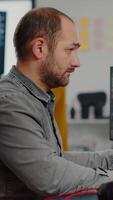 Videographer looking at camera smiling working in creative startup workplace using editing post production software on professional pc with two monitors, processing editing film footage. video
