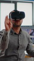 editor experiencing virtual reality headset, gesturing, editing film montage using post production software working in creative agency office. Videographer using VR goggles in multimedia company video