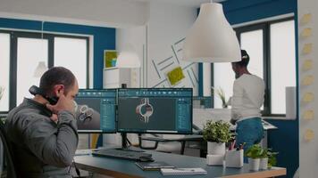 Mecanic technician working on cad software using computer with two monitors innovating an efficient eco-friendly motor prototype. Industrial man engineer studying new idea in creative office video