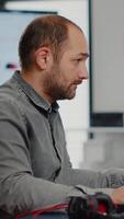 Man editor looking at camera, working with footage and sound on computer with two displays. Videographer editing movie smiling at camera, using app software for film montage in startup office. video