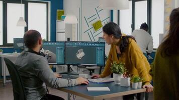 equipe do engenheiros falando dentro frente em pc com cafajeste Programas e dois monitores trabalhando dentro começar acima companhia inovando a eficiente ecológico motor protótipo. industrial arquitetos partilha Ideias. video