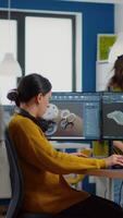 Happy woman mechanical engineer putting on headphones listening music while works on computer with screens showing CAD Software with 3D Prototype of gears shape and metalic mechanical piece. video