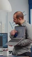 Man project supervisor holding laptop and pointing on display showing to woman industrial engineer who works on computer the development of new machinery prototype. Team working in creative office video