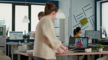Business employee using laptop in call conference with manager talking about company turnover standing at desk. Woman in busy office discussing with executive over internet regarding sales. video