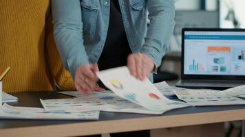 Selective focus on coworkers hands going through business papers with sales charts and key profit indicators on desk. Detail view of colleagues comparing marketing statistics and working on strategy. video