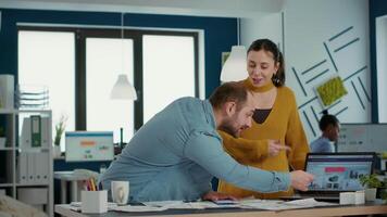 Smiling colleagues in startup office doing high five hand gesture celebrating business success standing at desk. Happy coworkers enjoying good results of team work looking at laptop with charts. video