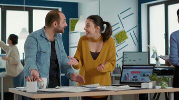 Smiling coworkers in startup office doing high five hand gesture celebrating good sales and high profit standing at desk. Happy colleagues enjoying team work looking at business papers with charts. video