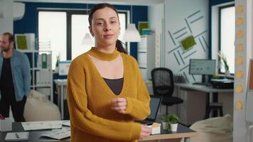 Portrait of confident startup employee entering frame posing with arms crossed and smiling in busy modern office. Business woman acting casual and relaxed in financial department of small company. video