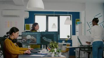 Industrial engineer putting on headset using pc with two monitors, screens showing CAD software with 3D Prototype of gears metalic mechanical piece. Employee working in creative agency office video