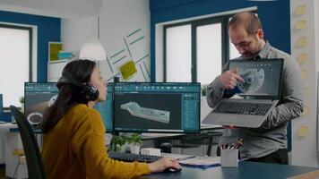 Engineer holding laptop and pointing on display showing to manager 3D gears image working in CAD program, compering with components from pc software. Team analysing technical prototype project video