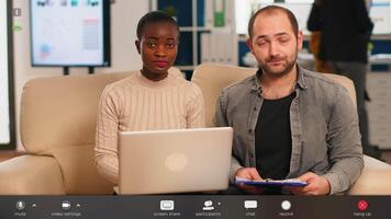 POV of diverse colleagues discussing about financial strategy during meeting using webcam sitting on couch in start up office. Coworkers analysing reports, footage with software overlay concept video