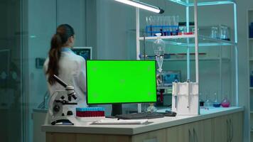 computador com verde tela trabalhando dentro laboratório com zombar acima monitor, croma chave exibição enquanto profissional engenheiro teste vírus evolução dentro fundo. Alto tecnologia desenvolvimento laboratório. video
