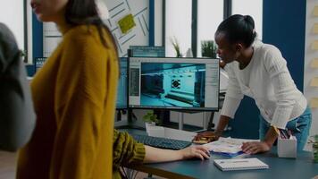 Mixed races of game creators testing the interface of videogame, analysing software problems. Diverse team developing project sitting in startup creative agency company using pc with two monitors video