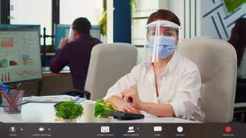 Businesswoman with visor and mask talking in front of camera having call with partners. Pov of manager speaking with remotely team during online conference, footage with software overlay concept video