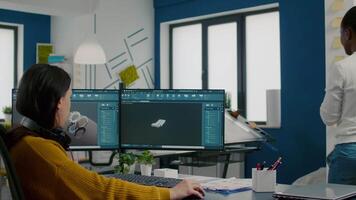 Industrial designer discussing with colleague holding tablet with in CAD program, designing 3D prototype of building. Woman engineer using pc with two monitors sharing ideas for construction mechanism video