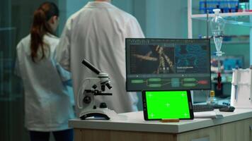 Tablet with green screen working in labooratory with mock up, chroma key display while professional engineer testing virus evolution in background. High tech development lab with blood samples video