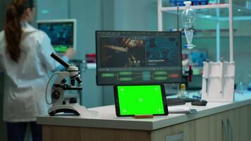 Notepad with green screen working in labooratory with mock up monitor, chroma key display while professional engineer testing virus evolution in background. High tech development lab. video