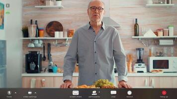 Senior man having call in kitchen while his family prepares the dinner. Pov online internet conference, chatting, communication, chat conversation call via webcam, footage with software overlay video