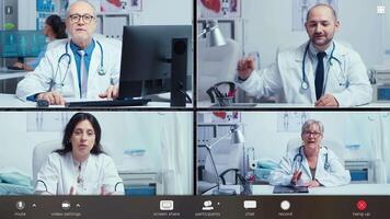 Pc screen webcam view, head shot portrait four medical workers in white coats take part in distant talk, engaged in group call. Videoconferencing, concilium remote communication concept. video
