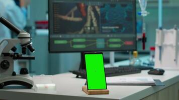 smartphone med grön skärm arbetssätt i laboratorium med falsk upp, krom nyckel visa medan professionell ingenjör testning virus Evolution i bakgrund. hög tech utveckling labb med blod prover video